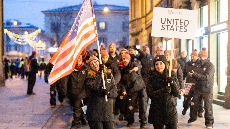 Lauren carrys US flags with USA team members behind her.